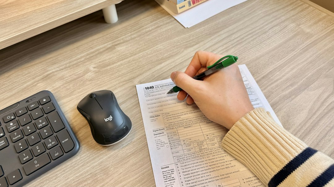 A hand filling in an incident record form at a desk beside a keyboard and mouse
