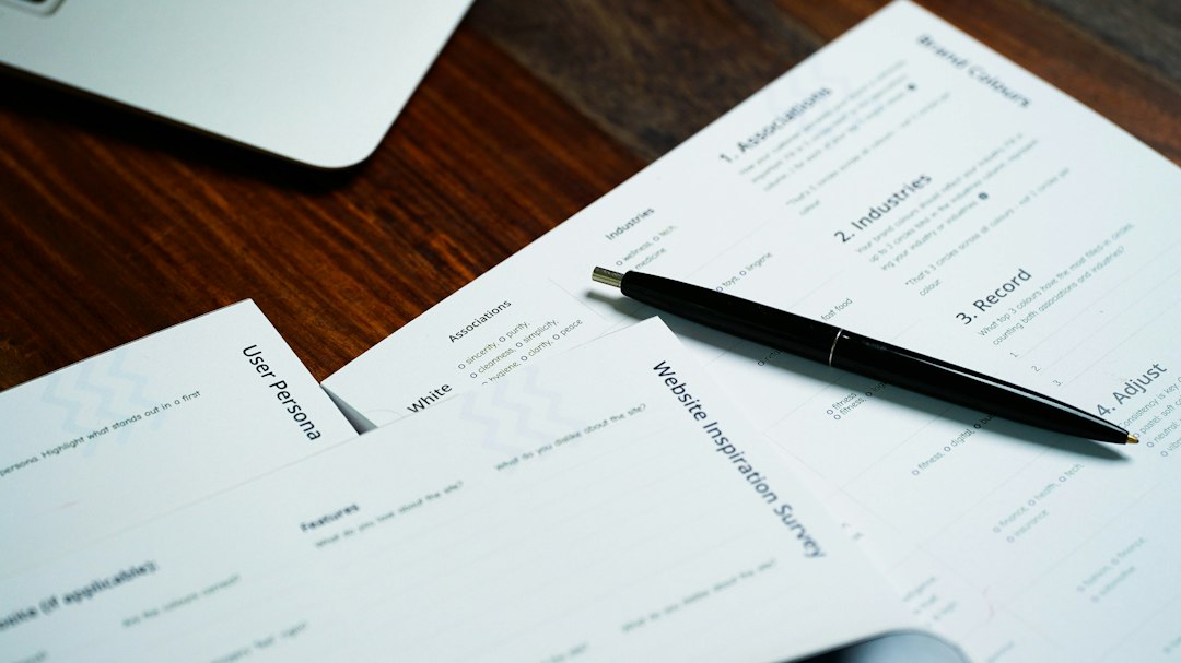 A pen resting on a printed form next to a laptop