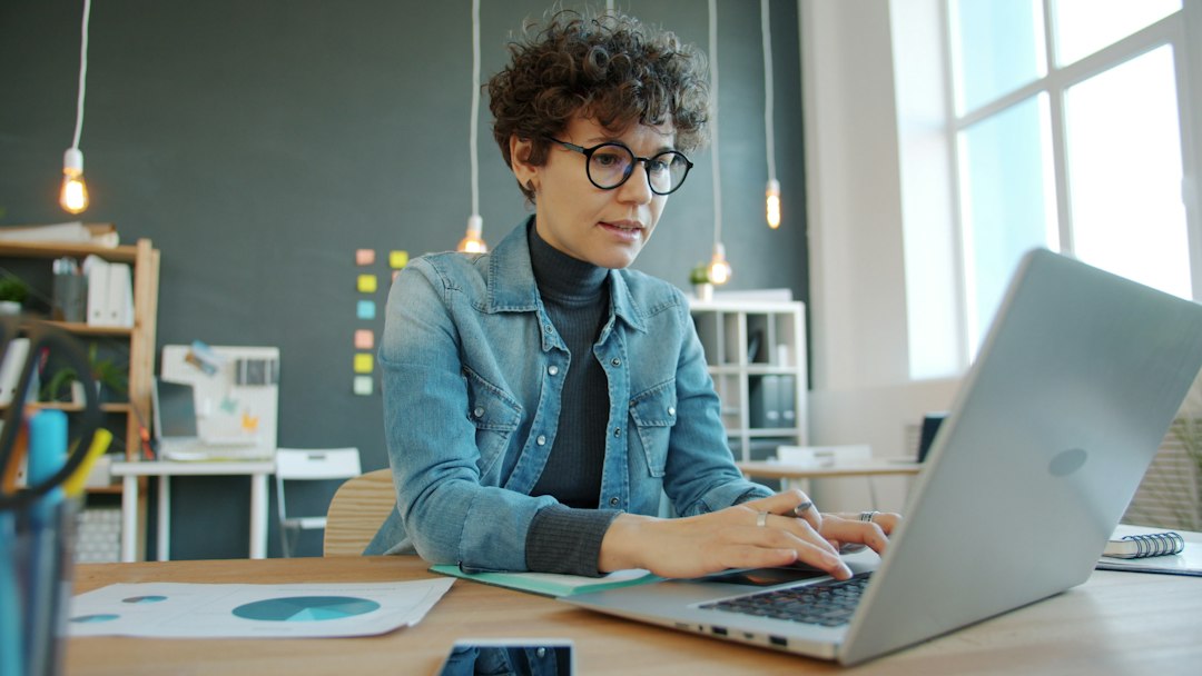 A person working intently on a laptop in a modern office