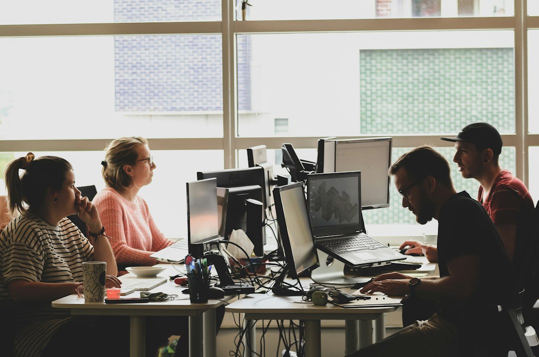 A team working at computers in a sunlit office, representing day-to-day operation of the AI management system