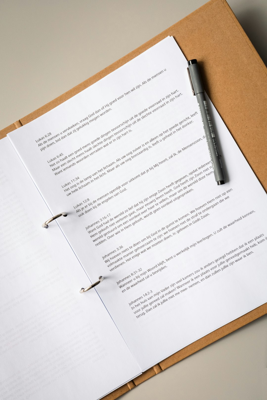 An open binder holding a typed document with a pen resting on the page
