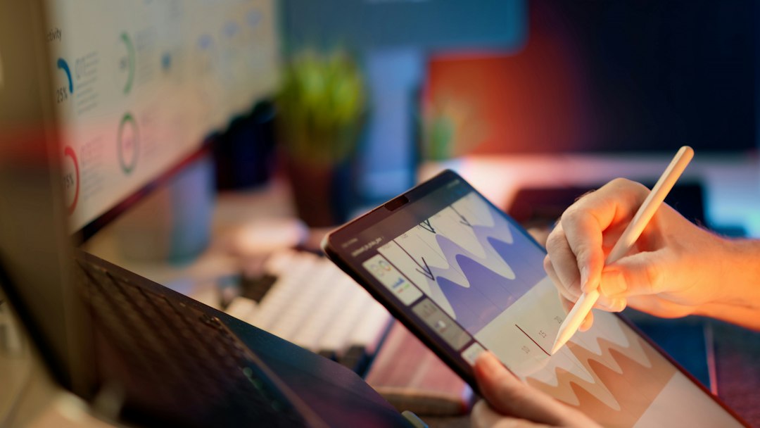 A hand analyzing data on a tablet in an office setting