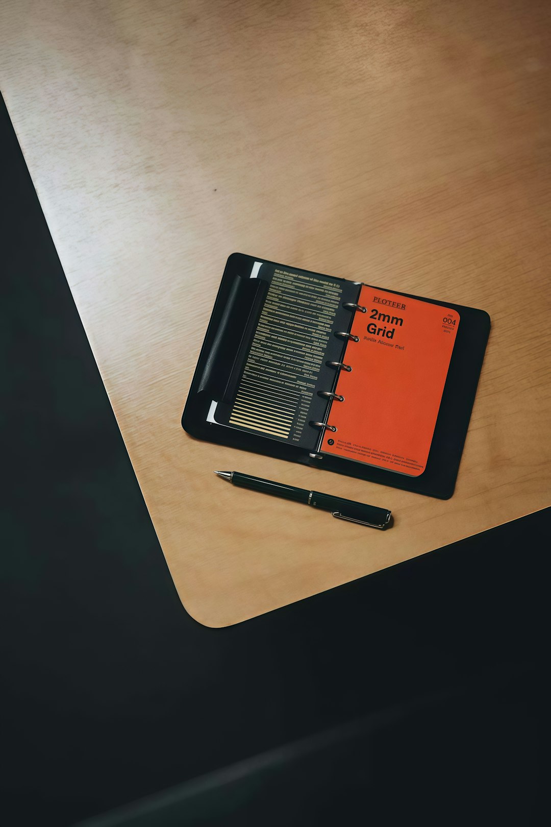 A black planner with a pen on a desk, anchoring the annual review to a fixed date