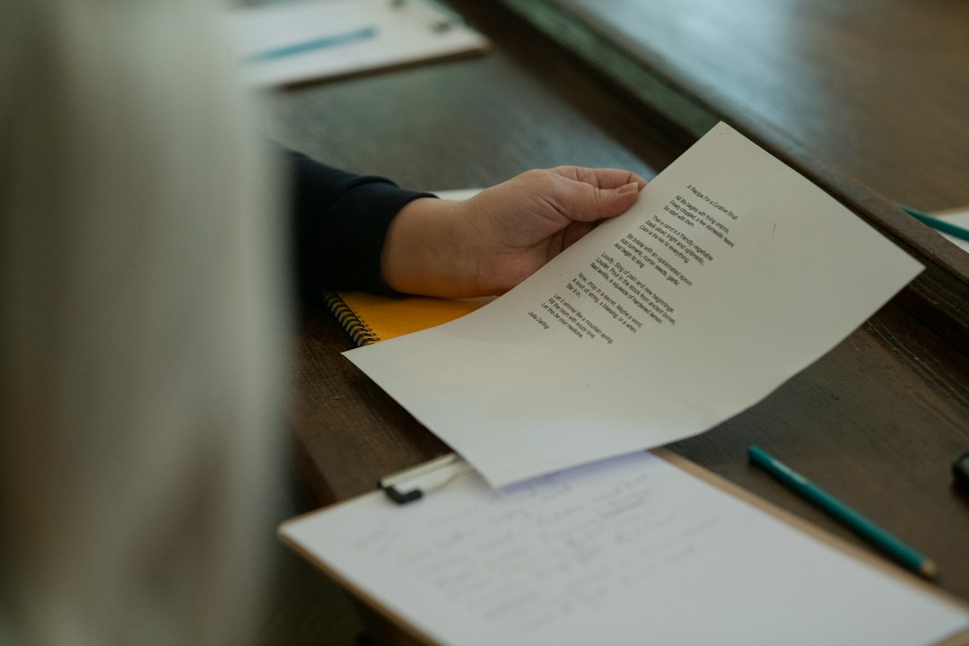 A hand holding a printed document over a clipboard