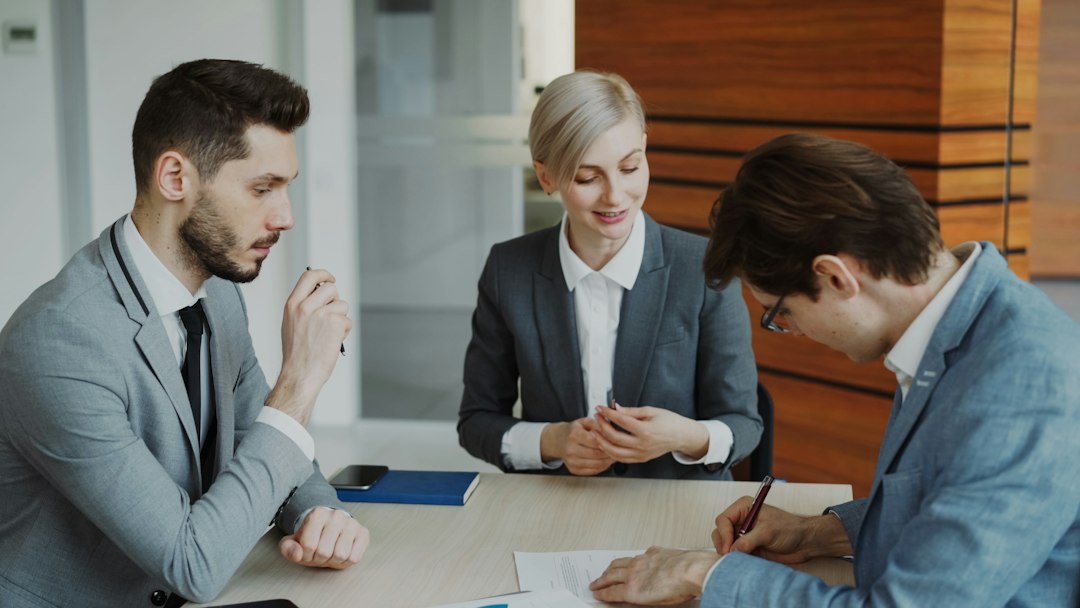 Three professionals signing a document in an office meeting