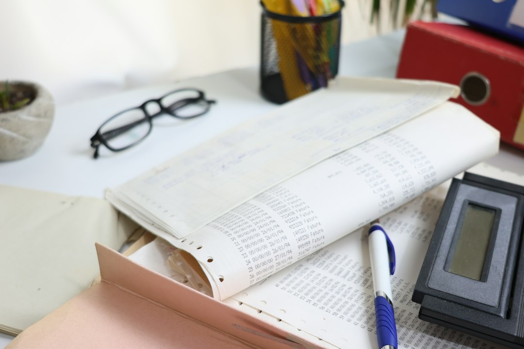 A desk with papers, glasses, and a calculator